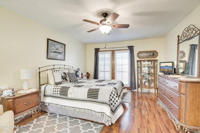 bedroom with a textured ceiling, ceiling fan, and light hardwood / wood-style flooring