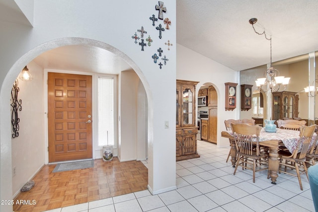 dining room featuring lofted ceiling, a textured ceiling, a chandelier, and light parquet floors