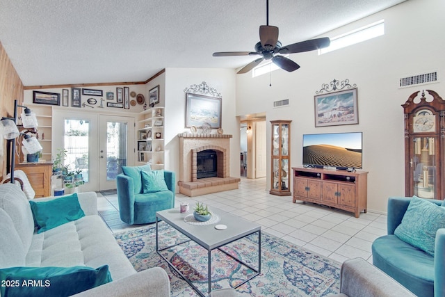 tiled living room featuring french doors, ceiling fan, built in shelves, and a textured ceiling