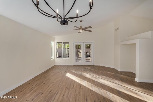 unfurnished living room with lofted ceiling, wood-type flooring, ceiling fan with notable chandelier, and french doors