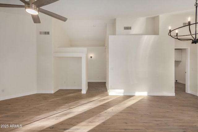 unfurnished room with hardwood / wood-style floors, ceiling fan with notable chandelier, and high vaulted ceiling