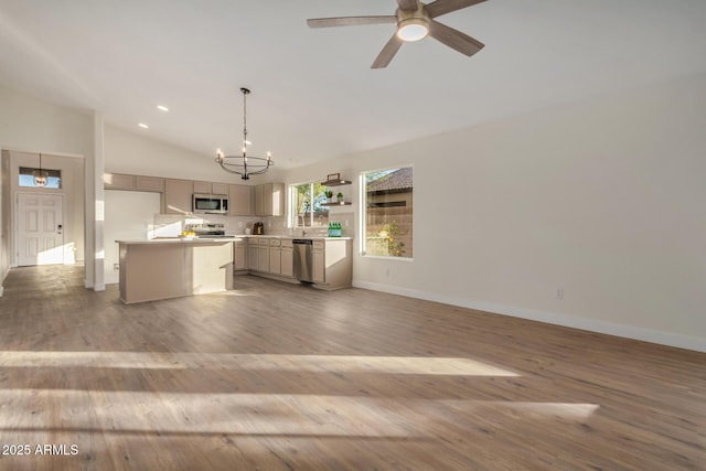 kitchen with hanging light fixtures, stainless steel appliances, light hardwood / wood-style flooring, a kitchen island, and ceiling fan with notable chandelier