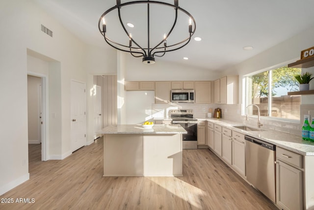 kitchen with a center island, sink, stainless steel appliances, pendant lighting, and a chandelier