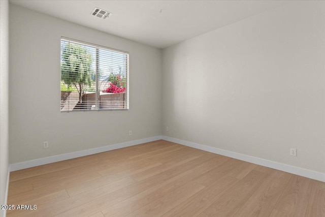 empty room with visible vents, light wood-style flooring, and baseboards