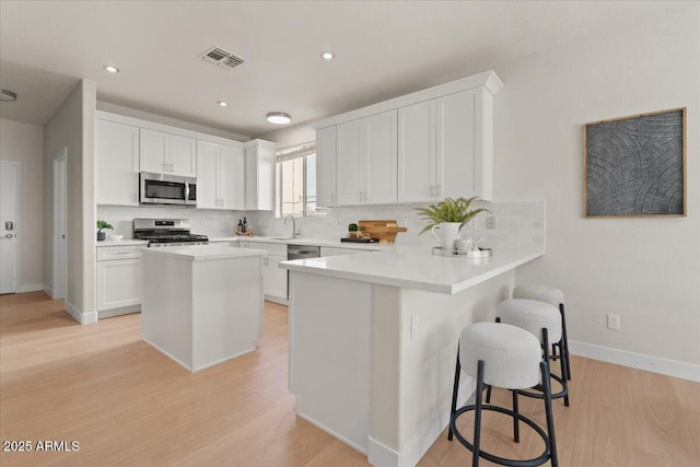 kitchen with a sink, appliances with stainless steel finishes, tasteful backsplash, and visible vents