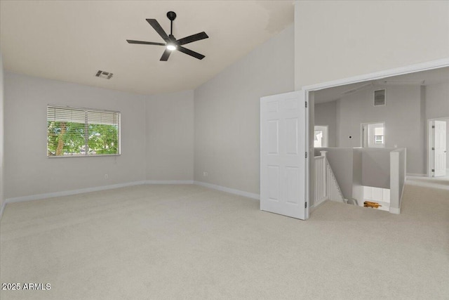 empty room with plenty of natural light, carpet floors, visible vents, and lofted ceiling