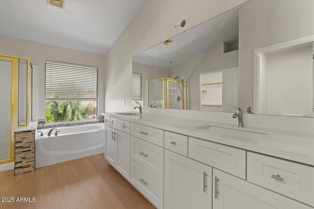 full bath with a sink, a shower stall, vaulted ceiling, and wood finished floors