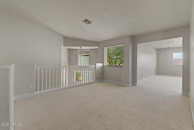 empty room featuring carpet floors, baseboards, vaulted ceiling, and visible vents