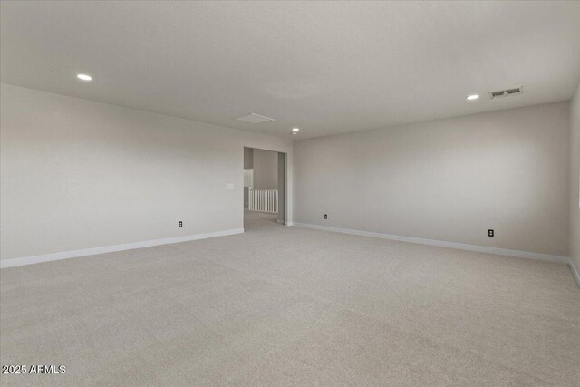 empty room featuring visible vents, baseboards, radiator, light carpet, and recessed lighting