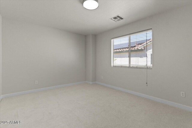 unfurnished room with light colored carpet, baseboards, and visible vents