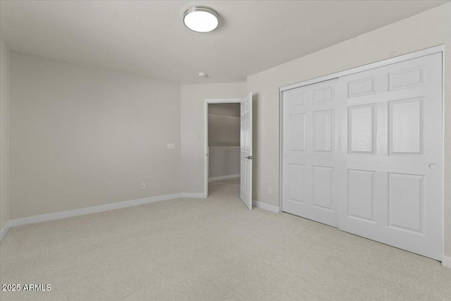 unfurnished bedroom featuring baseboards, a closet, and light colored carpet