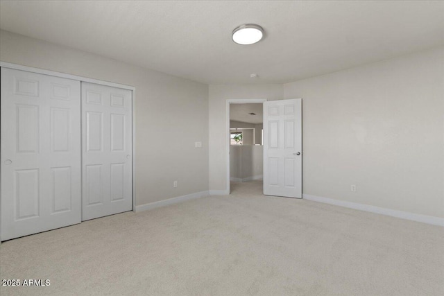 unfurnished bedroom featuring baseboards, light colored carpet, and a closet
