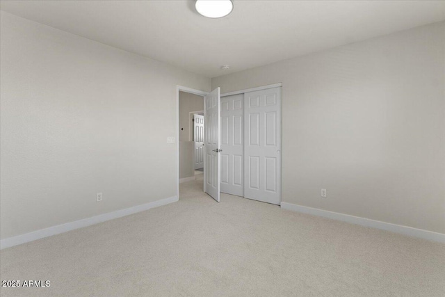 unfurnished bedroom with light colored carpet, baseboards, and a closet
