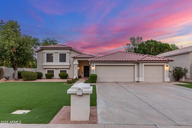 mediterranean / spanish house with stucco siding, driveway, a yard, a garage, and a tiled roof