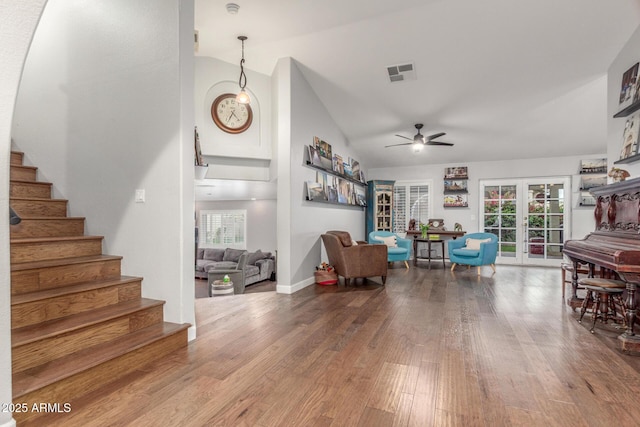 living room with stairway, wood finished floors, visible vents, high vaulted ceiling, and french doors