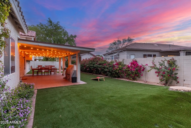 yard at dusk with a patio and fence