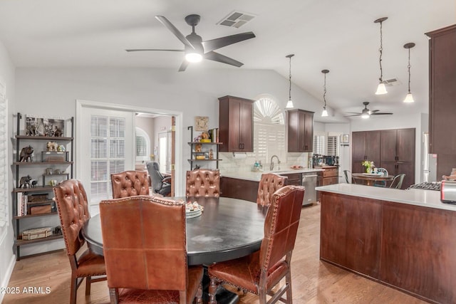 dining room featuring visible vents, ceiling fan, vaulted ceiling, and light wood finished floors