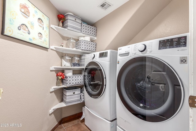 laundry room with tile patterned floors, visible vents, washer and dryer, baseboards, and laundry area