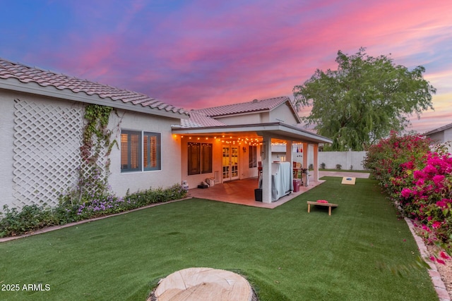 rear view of house with a yard, a fenced backyard, stucco siding, french doors, and a patio area