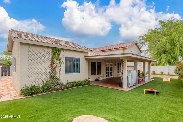 back of property with fence, a tile roof, stucco siding, a yard, and a patio area