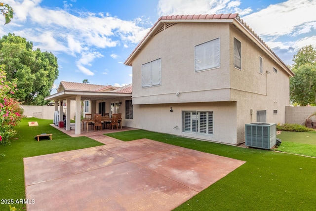 back of property with a lawn, cooling unit, a patio, and stucco siding