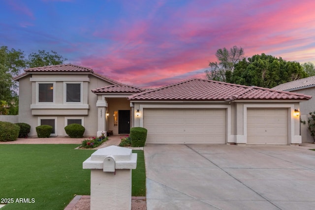 mediterranean / spanish home with stucco siding, a yard, concrete driveway, a garage, and a tiled roof