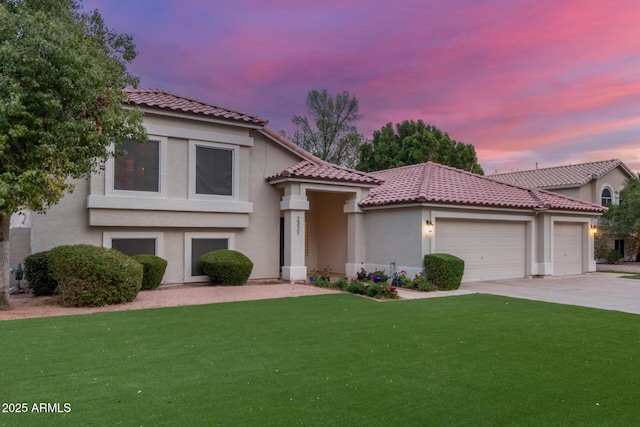 mediterranean / spanish house with driveway, a yard, stucco siding, a garage, and a tiled roof