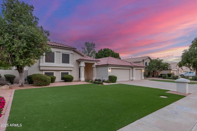 mediterranean / spanish-style home featuring a garage, stucco siding, concrete driveway, and a front lawn