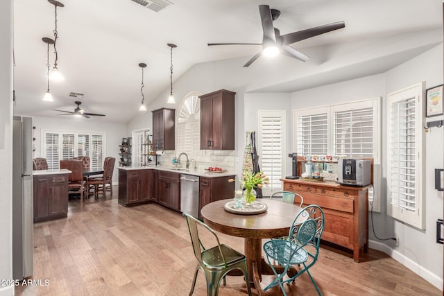 kitchen with light wood finished floors, light countertops, lofted ceiling, stainless steel appliances, and a sink