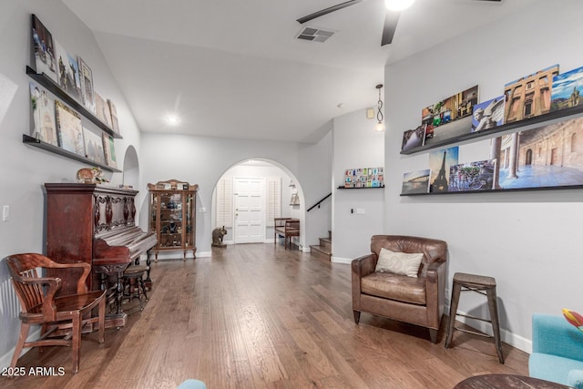 sitting room featuring visible vents, stairs, lofted ceiling, wood finished floors, and arched walkways