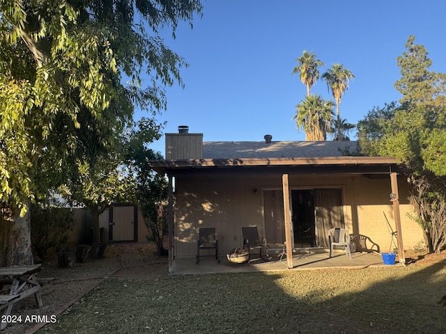 back of property featuring a yard, a shed, and a patio area