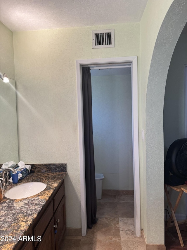 bathroom with vanity, toilet, and a textured ceiling