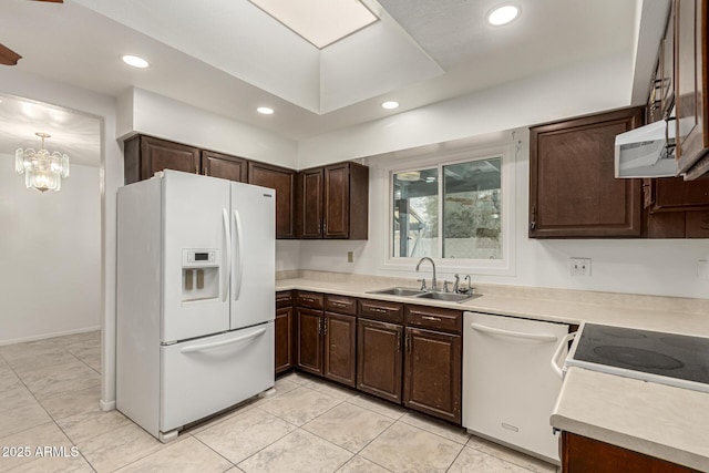 kitchen featuring dark brown cabinetry, white appliances, light countertops, a sink, and recessed lighting