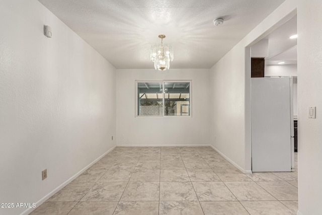 empty room featuring baseboards and an inviting chandelier