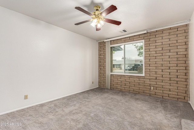 carpeted spare room with brick wall, visible vents, and ceiling fan