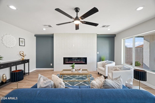 living room featuring ceiling fan, a fireplace, and light hardwood / wood-style floors