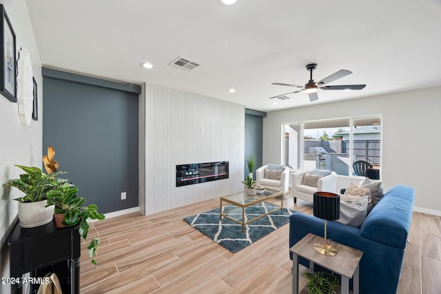 living room featuring ceiling fan and a large fireplace