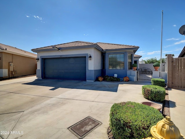 view of front of home featuring a tile roof, stucco siding, fence, a garage, and driveway