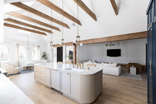 kitchen featuring white cabinets, sink, a kitchen island with sink, and hanging light fixtures