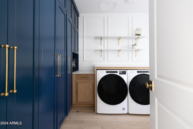 washroom featuring cabinets, light hardwood / wood-style flooring, and washing machine and clothes dryer