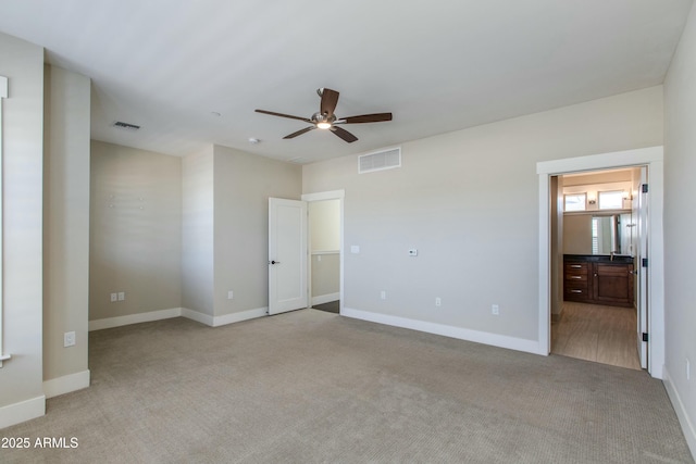 unfurnished bedroom featuring ceiling fan, light carpet, and ensuite bath