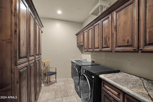 clothes washing area with washer and dryer, cabinets, and sink