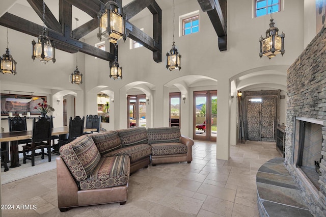 living room featuring a towering ceiling, a fireplace, and french doors