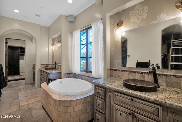 bathroom with vanity and tiled bath