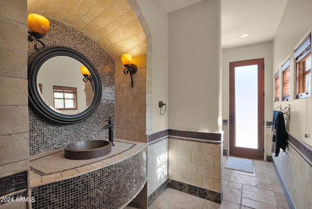 bathroom with plenty of natural light and tile walls