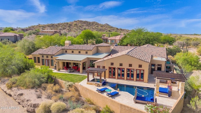 back of house featuring a mountain view, a fenced in pool, and a patio area