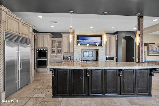 kitchen with pendant lighting, light stone counters, a spacious island, and stainless steel appliances