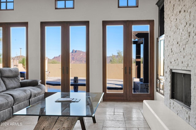 living room featuring a mountain view, a healthy amount of sunlight, a stone fireplace, and french doors