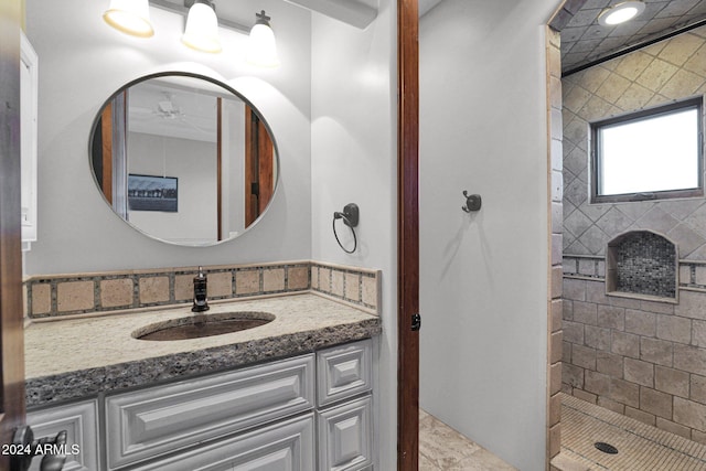 bathroom featuring tiled shower, vanity, tile patterned floors, and ceiling fan