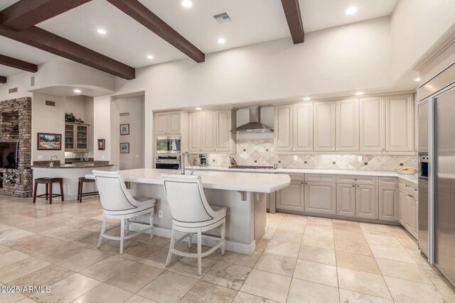 3205 S Ponderosa Dr, Gold Canyon, AZ 85118 - kitchen with tasteful backsplash, visible vents, wall chimney range hood, a kitchen bar, and beamed ceiling